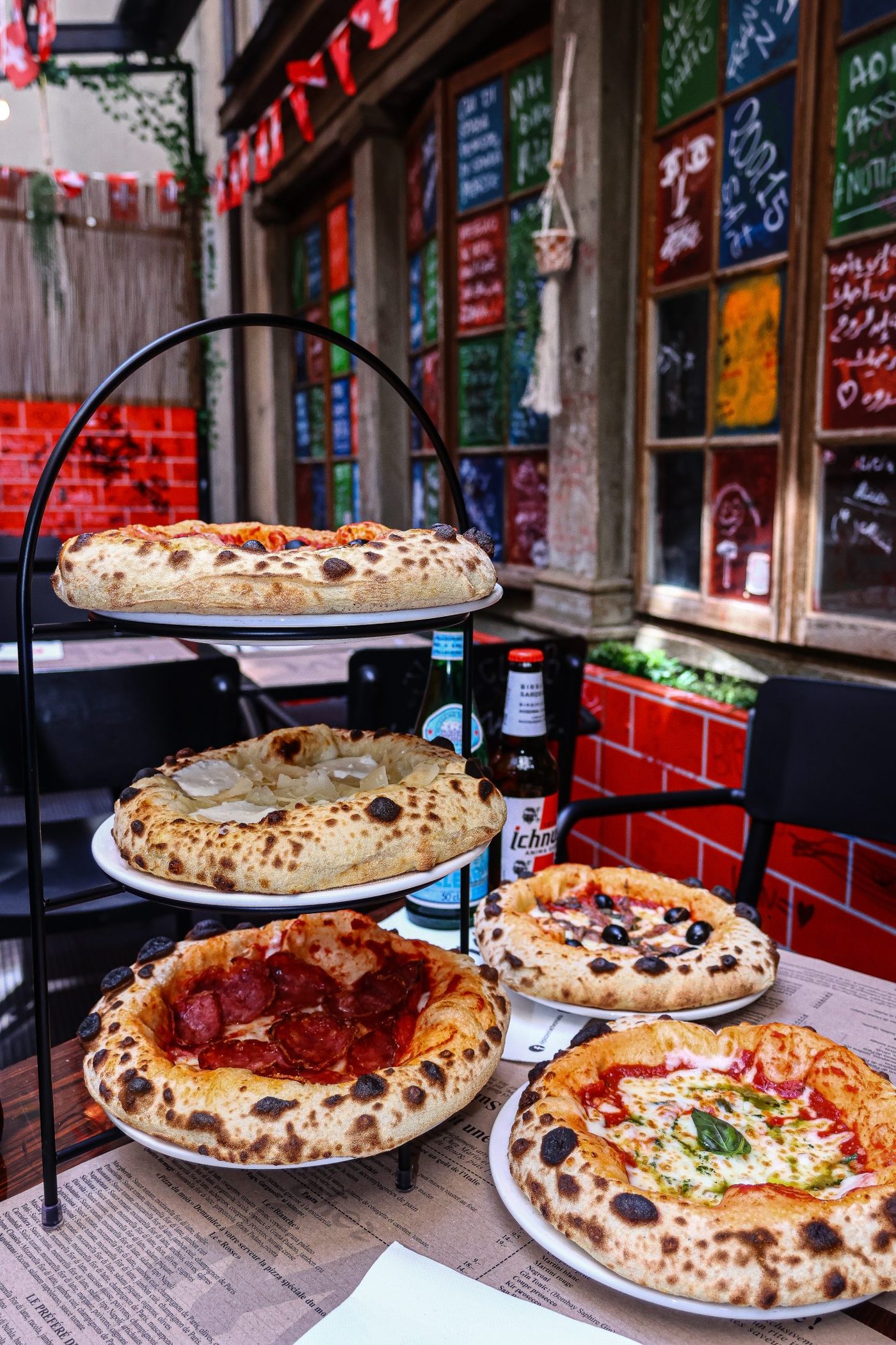 Plusieurs pizzas dressées devant l'ardoise du jour