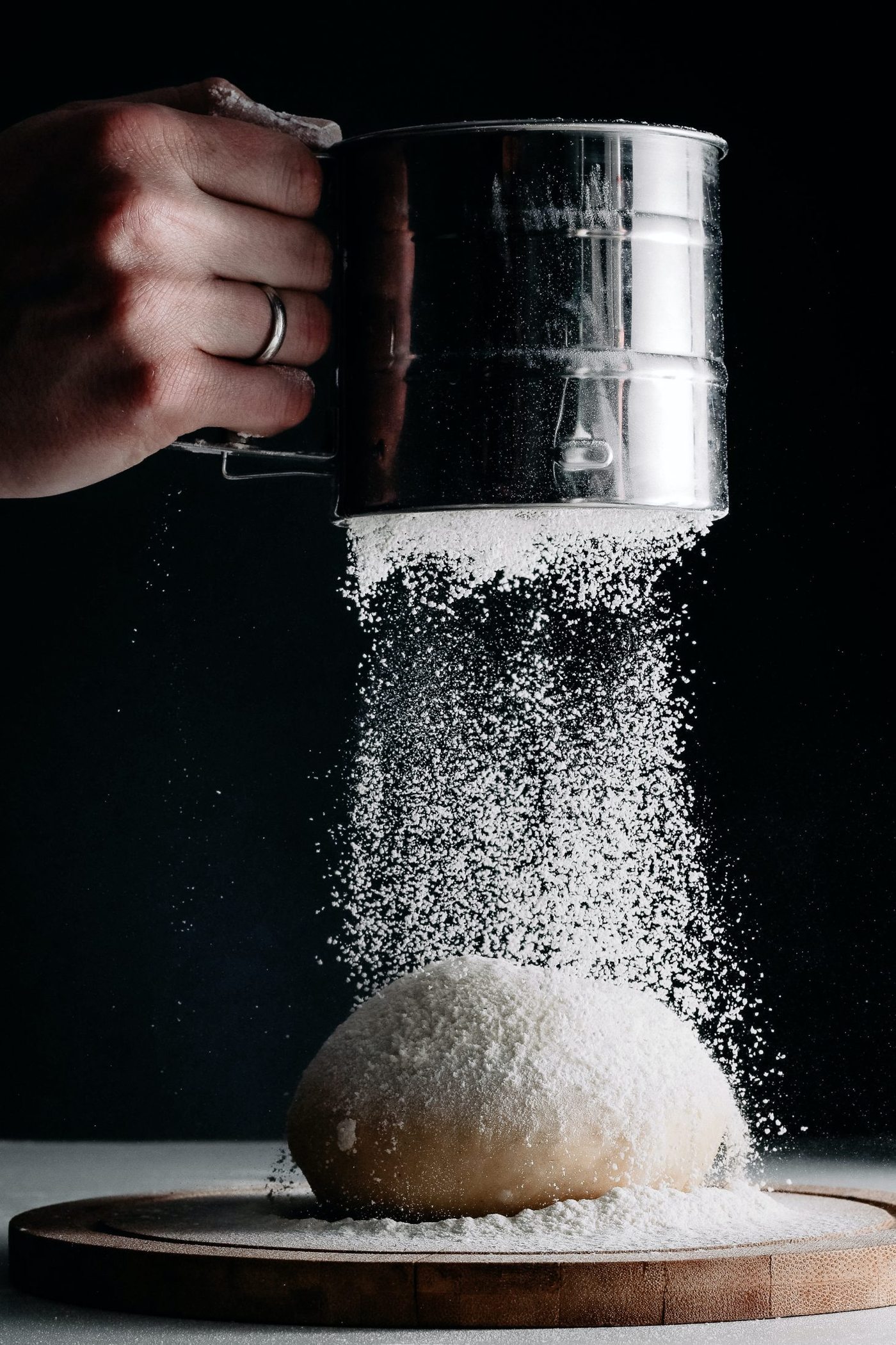 La farine versée au tamis sur la boule de pâte