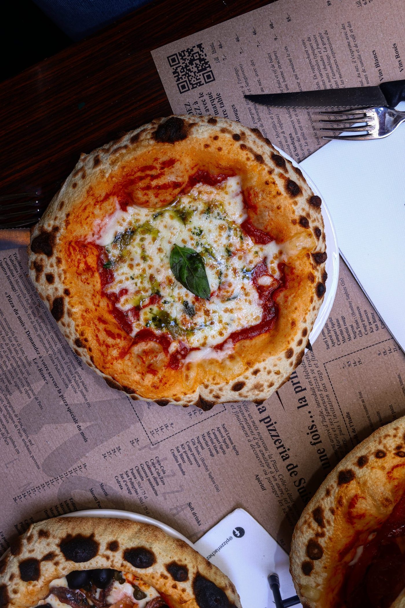 Une pizza sortie du four, vue de dessus sur le set de table de la maison