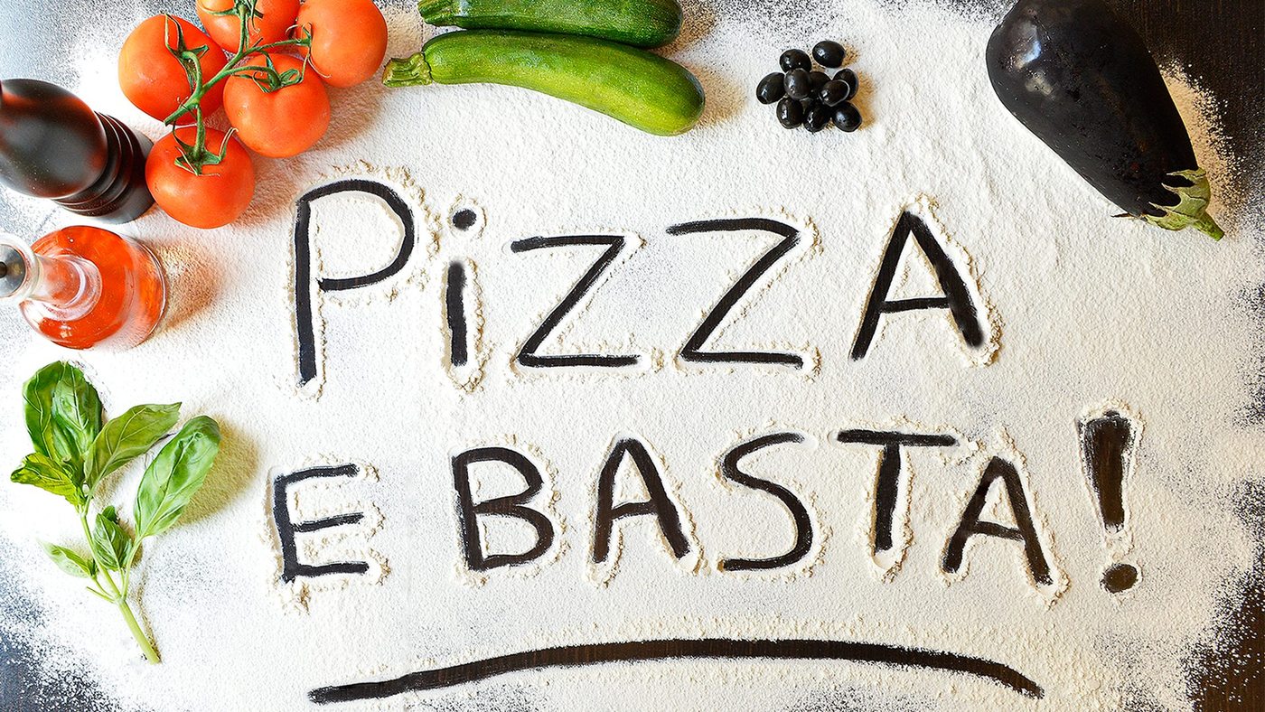 « Pizza e basta » écrit à la farine, entouré de tomates, basilic et légumes