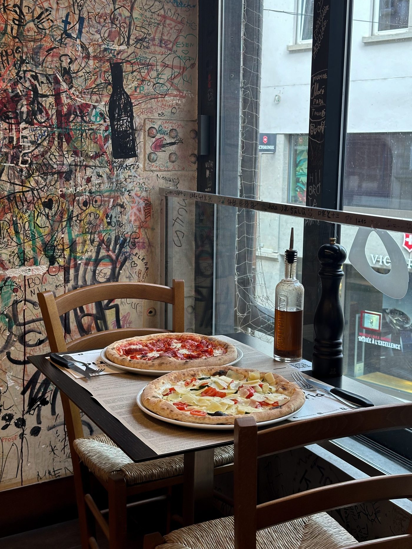 Deux pizzas sur une table devant la fenêtre, rue de Bourg