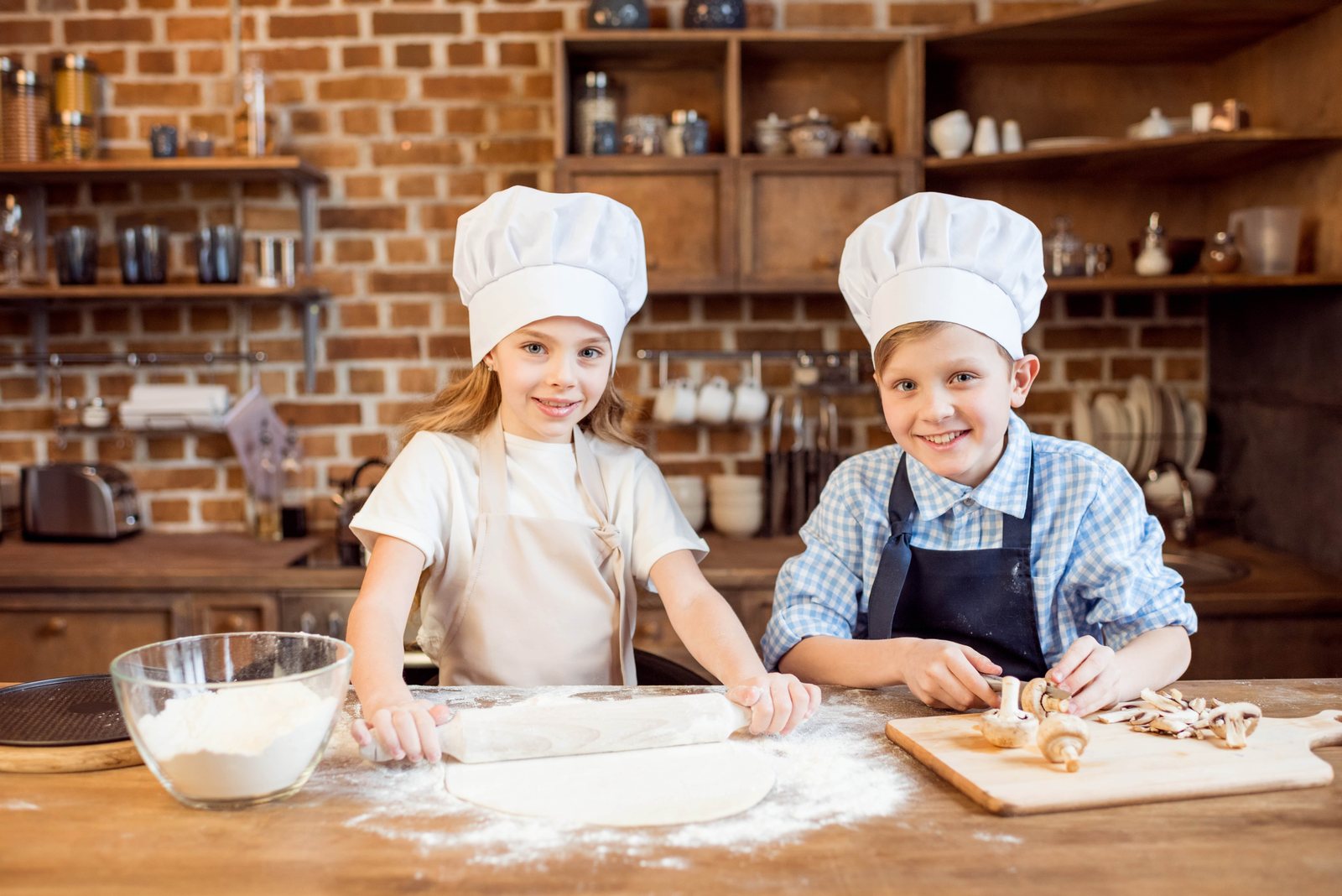 Deux enfants en toque préparent leur pizza à l'atelier Pizza Kids Academy