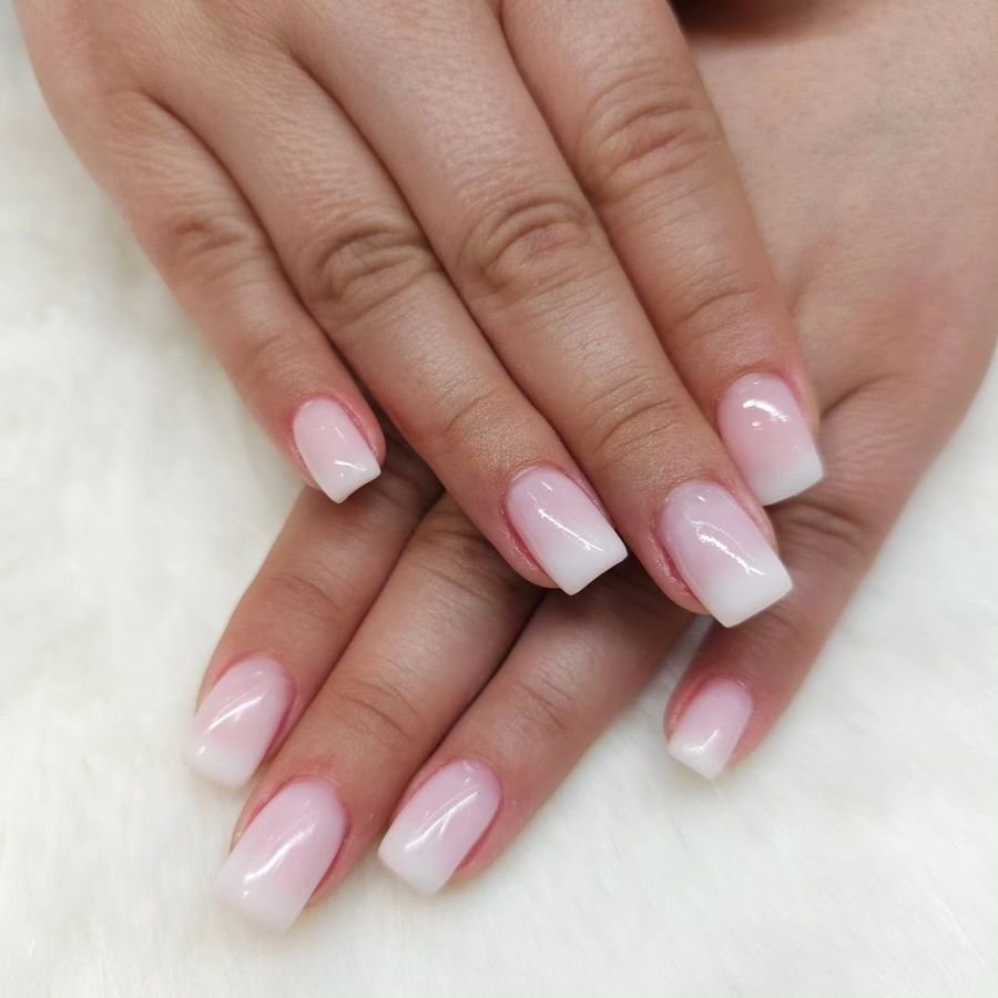 Mains aux ongles en dégradé rose et blanc
