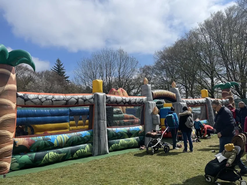 Grand château gonflable thématisé dinosaures avec des familles à Dino World