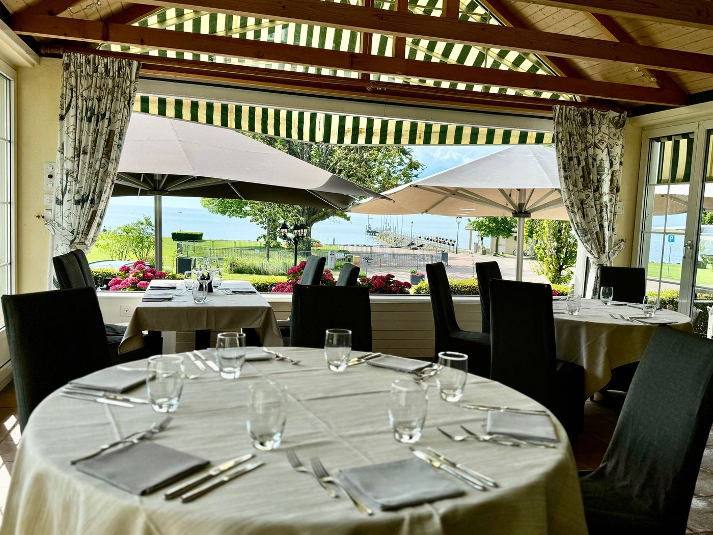 La terrasse du Débarcadère dressée face au lac Léman, stores rayés et vue sur les Alpes