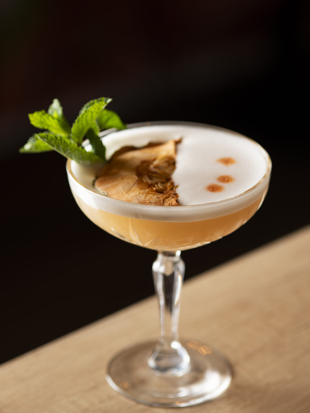 Cocktail signature servi au bar, mousse et garniture fraîche