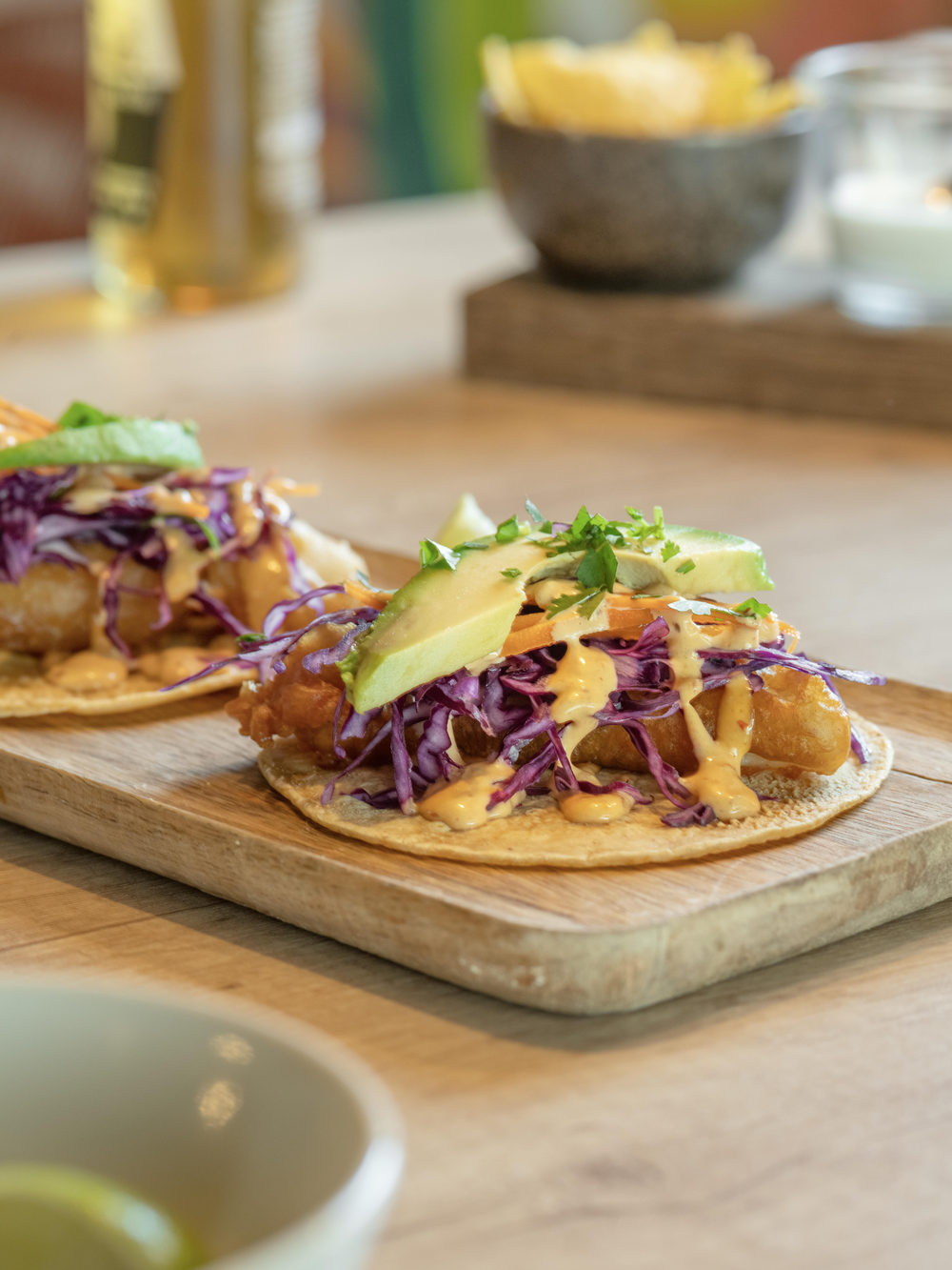 Tacos garnis de chou rouge, avocat et sauce, servis sur planche