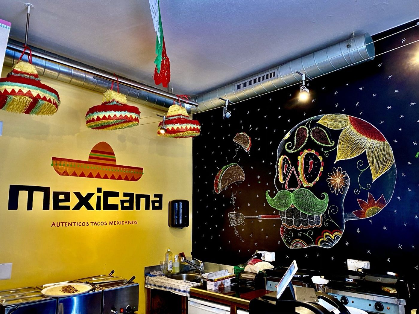 Intérieur du restaurant Mexicana à Lausanne, fresque tête de mort et piñatas sombrero